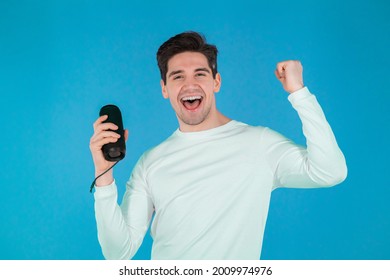 Man Listening To Music By Wireless Portable Speaker - Modern Sound System. Young Guy Dancing, Enjoying At Blue Studio Background. He Moves To The Rhythm Of Music