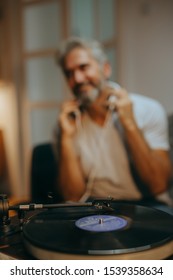 Man Listening Music On Record Player In His Room