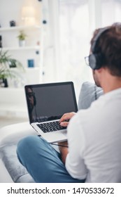 Man listening to music and using laptop in the living room. - Shutterstock ID 1470533672