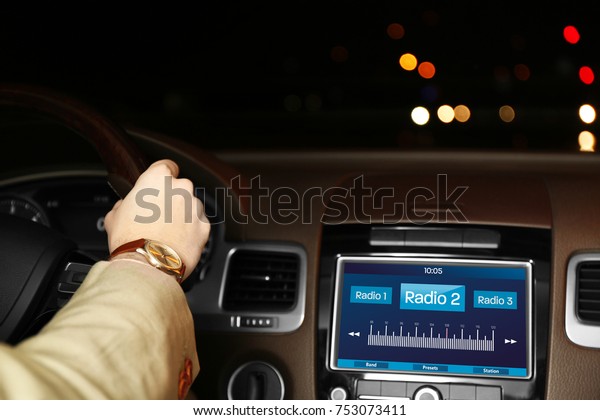 Man\
listening to radio while driving car at\
night