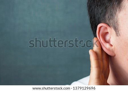 The man listens attentively with her palm to her ear, close up, the news concept