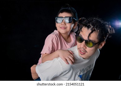 Man And Little Boy With Sunglasses Standing Looking Camera  On Dark Studio Background , Asian Family