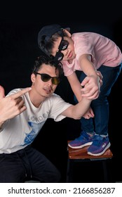 Man And Little Boy With Sunglasses Standing Looking Camera  On Dark Studio Background , Asian Family