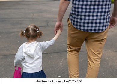 Man with little girl are walking in the summer street. Father and daughter are holding each other's hand. Summer family time concept