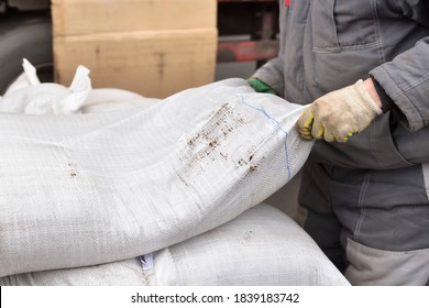 A Man Loader At A Factory Raises A Heavy Bag With His Hands