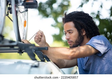 Man In Loading Bike On A Car Roof