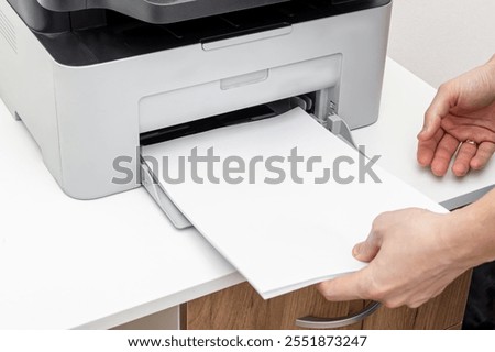 A man loading paper into printer. White a4 printing paper