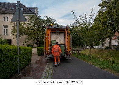 Man Loads Garbage Cans Into A Garbage Truck. Selective Focus. Blurred Background