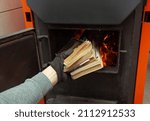 Man loads the old books in the solid fuel boiler in the boiler room. Solid fuel and heating concept 