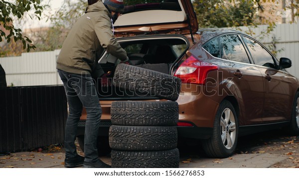 A man loads winter tires\
in a car trunk. Motorist prepares changes car tires from summer to\
winter