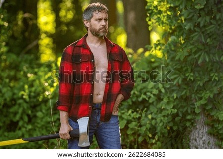 Man with logging axe. Brutal man in unbuttoned shirt. Lumberjack hardworking outdoor. Brutal lumberjack, copy space. Brutality and masculinity. Hispanic lumberjack man with axe. Lumberjack axe