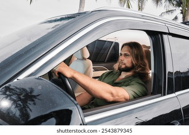 Man with long hair driving a black car under palm trees - Powered by Shutterstock