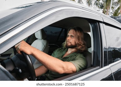 Man with long hair driving a car by palm trees in a tropical setting - Powered by Shutterstock