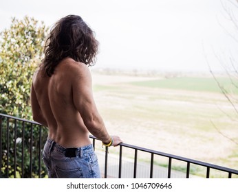 Man With Long Hair On A Roof Showing His Back