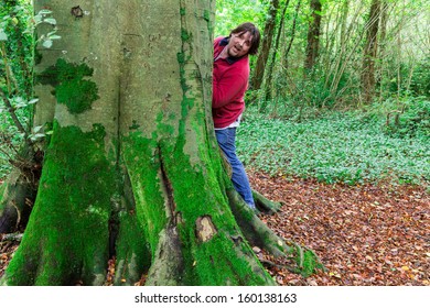 Man Looking Around A Tree Paying Hide And Seek In A Forest