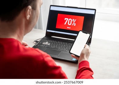 A man is looking for a bargain on a laptop and smartphone with discounts on Black Friday. The concept of online shopping - Powered by Shutterstock