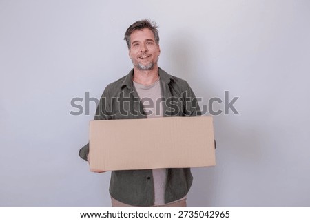 Man looking at camera, holding empty brown cardboard box, ready for packing, receiving, or displaying custom text and branding