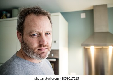 A man looking at the camera in the kitchen.