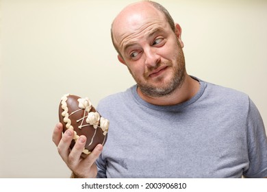 A Man Looking At A Chocolate Candy. Expression Of Being Tempted By A Sweet. Unhealthy Eating. Copy Space.