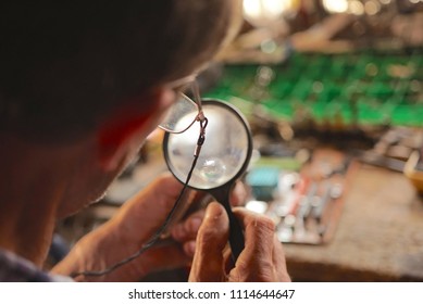 Man Looking At Circuit Board With Magnifying Glass                                - Shutterstock ID 1114644647