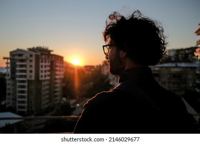 man looking at city sunset
