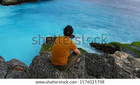 man looking at coral reef in rocky sea
