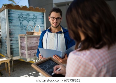 Man looking at coworker writing menu by food truck - Powered by Shutterstock