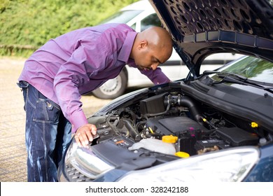 man looking at the engine of his car