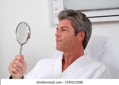 Man Looking In Hand Held Mirror