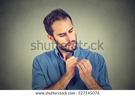man looking at hands nails obsessing about cleanliness germs isolated on gray background. Negative human emotion facial expression, feeling, life perception