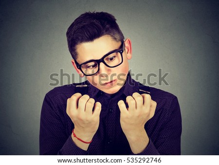 man looking at hands nails obsessing about cleanliness germs isolated on gray background. Negative human emotion facial expression, feeling, perception