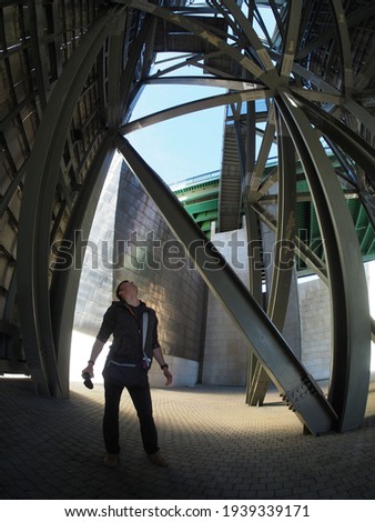 man looking up at an industrial structure