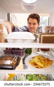 Man Looking Inside Fridge Filled With Food