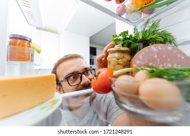 Man Looking Inside Fridge Full Of Food.