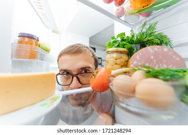 Man Looking Inside Fridge Full Of Food.