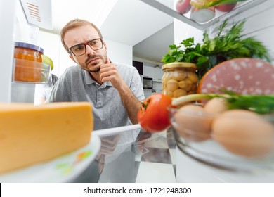 Man Looking Inside Fridge Full Of Food.