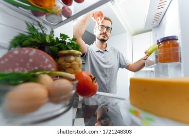 Man Looking Inside Fridge Full Of Food.