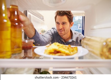 Man Looking Inside Fridge Full Of Unhealthy Food