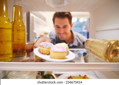 Man Looking Inside Fridge Full Of Unhealthy Food