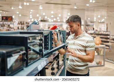 Man Looking Inside Microwave Oven In Shop