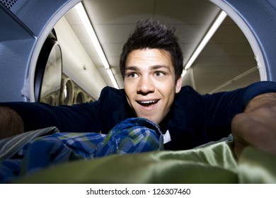 Man Looking Into Dryer At Laundromat With Clothing