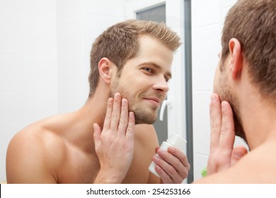 Man looking into the mirror and applying aftershave