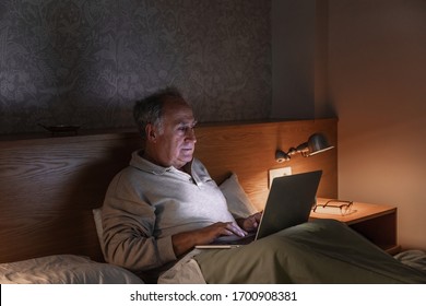 Man Looking At The Laptop From The Bed In His Room At Night