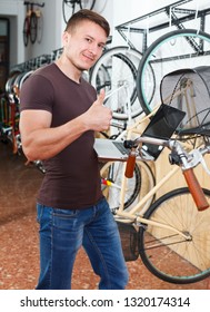 Man Is Looking In Laptop And Choosing Modern Bicycle In The Bike Store.