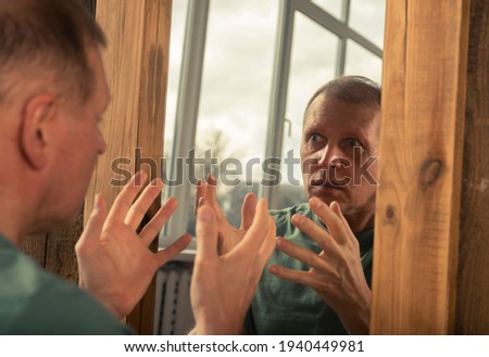 Man looking in mirror in anger and rage and shouting at him self. Psychological problem concept.