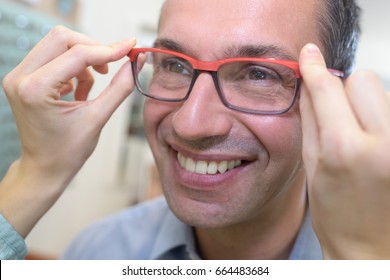 Man Looking In The Mirror While Trying On Glasses