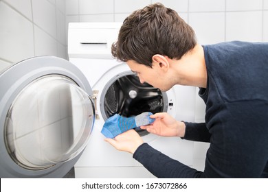 Mann auf der Suche nach fehlenden Socken in der Waschmaschine und fand nur eine blaue Socke