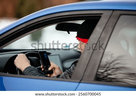 Man looking at mobile phone while driving a car.