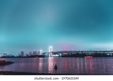 Man Looking Night City And Bridge From Sea Beach