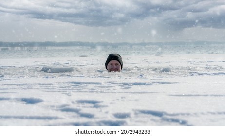 A man looking out of an ice hole while having an ice bath in a frozen lake